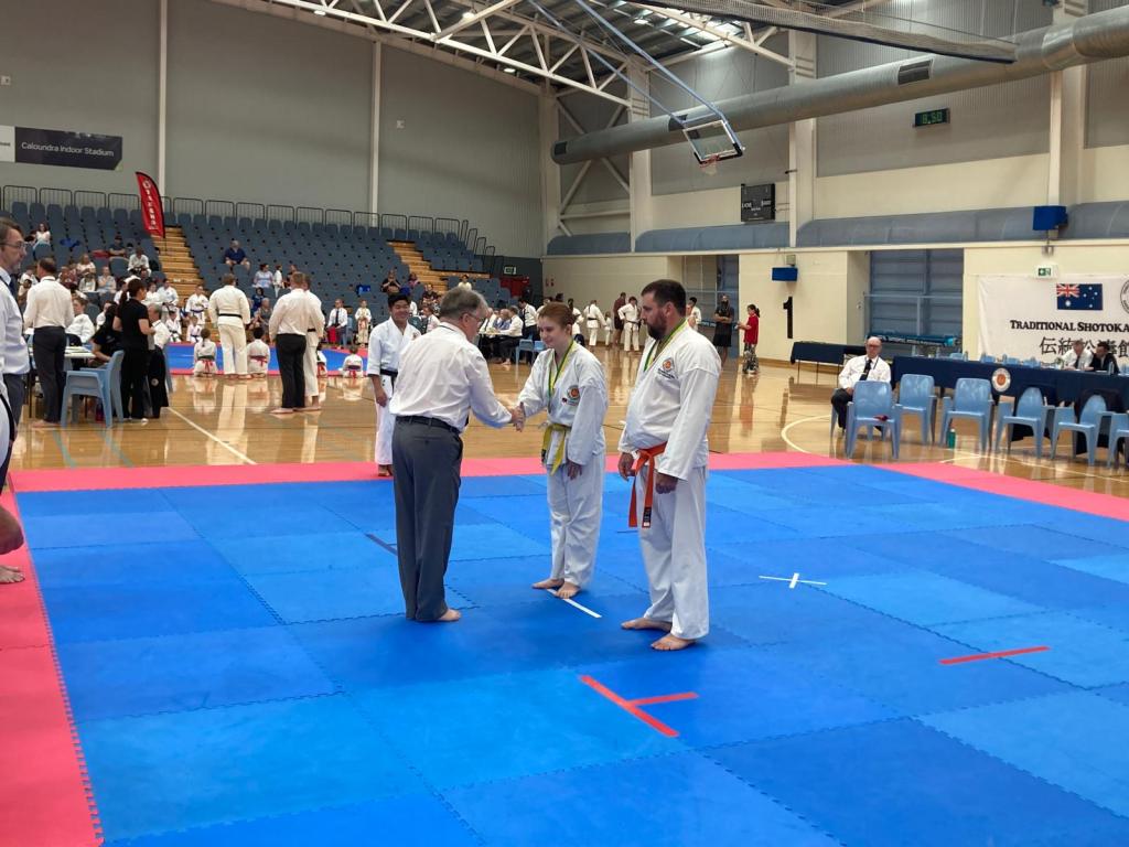 A women is shaking hands with a judge and is wearing a medal. 